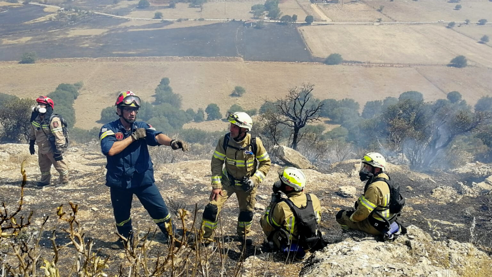 Kreikan maastopalojen sammutukseen osallistuvat Suomalaiset pelastustyöntekijät saavat ohjeita savuisessa maastossa. Kuvassa viisi henkilöä varusteet päällä. 