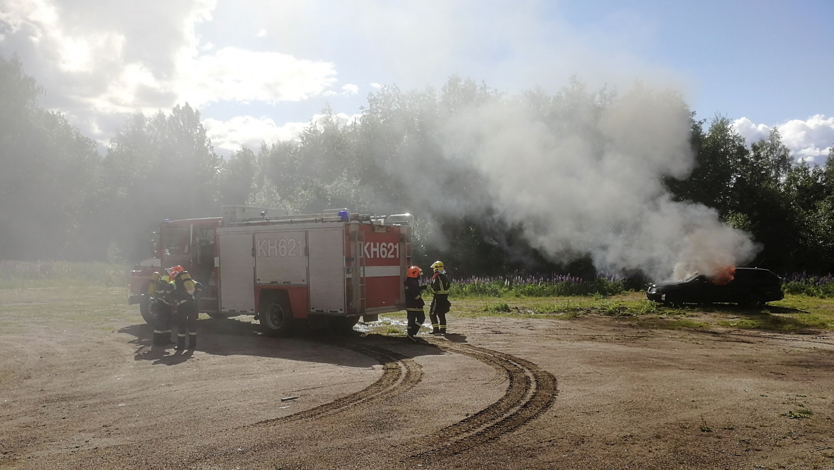 Palokuntanuoret harjoittelevat palavan auton sammutusta.