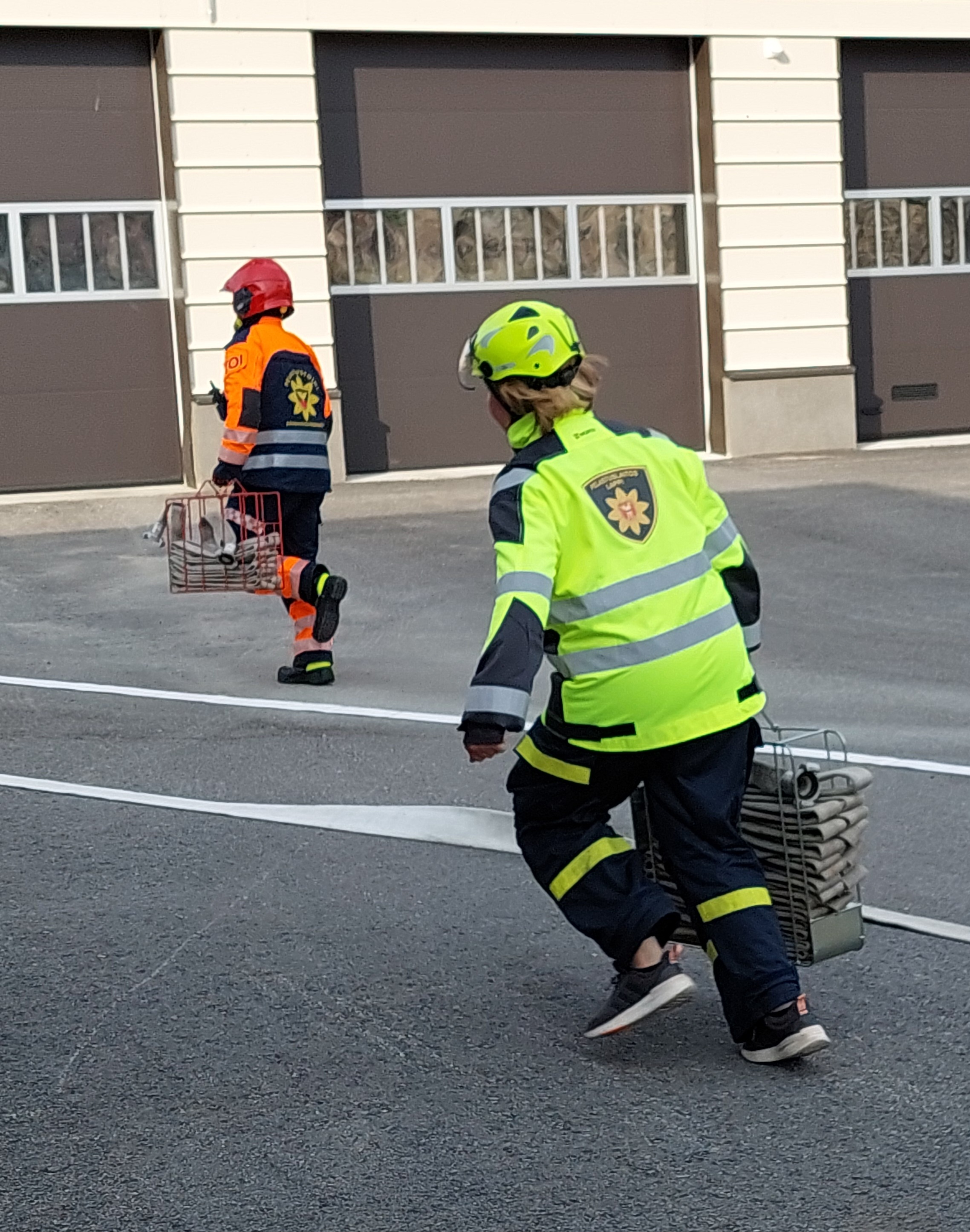 Palokuntanuori ja hälytysosastolainen juoksevat ja kantavat letkukehikoita.