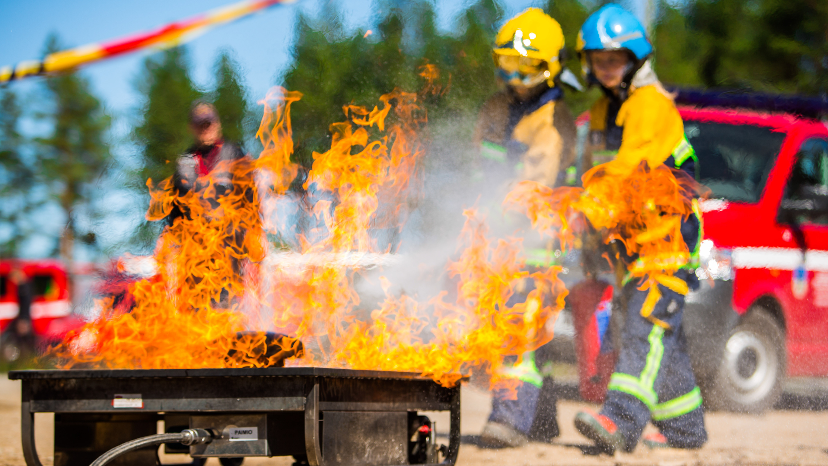 Palokuntanuoret sammuttavat harjoitustilanteessa roihuavaa tulta.
