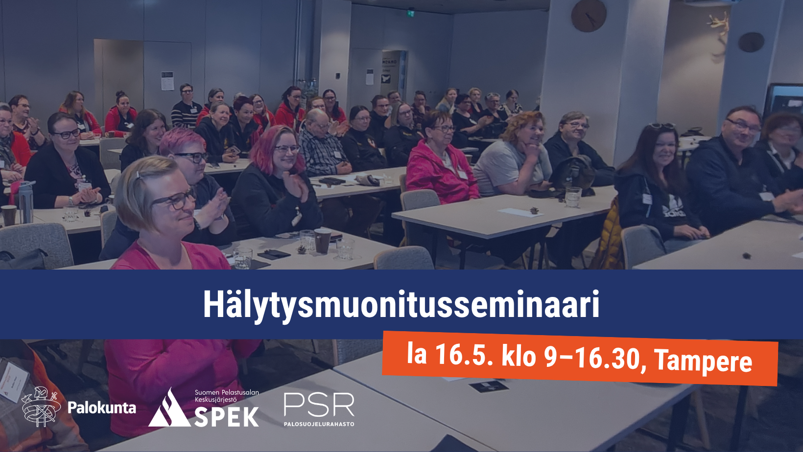 Hälytysmuonitusseminaarin osallistujat istuvat kokoustilassa.	