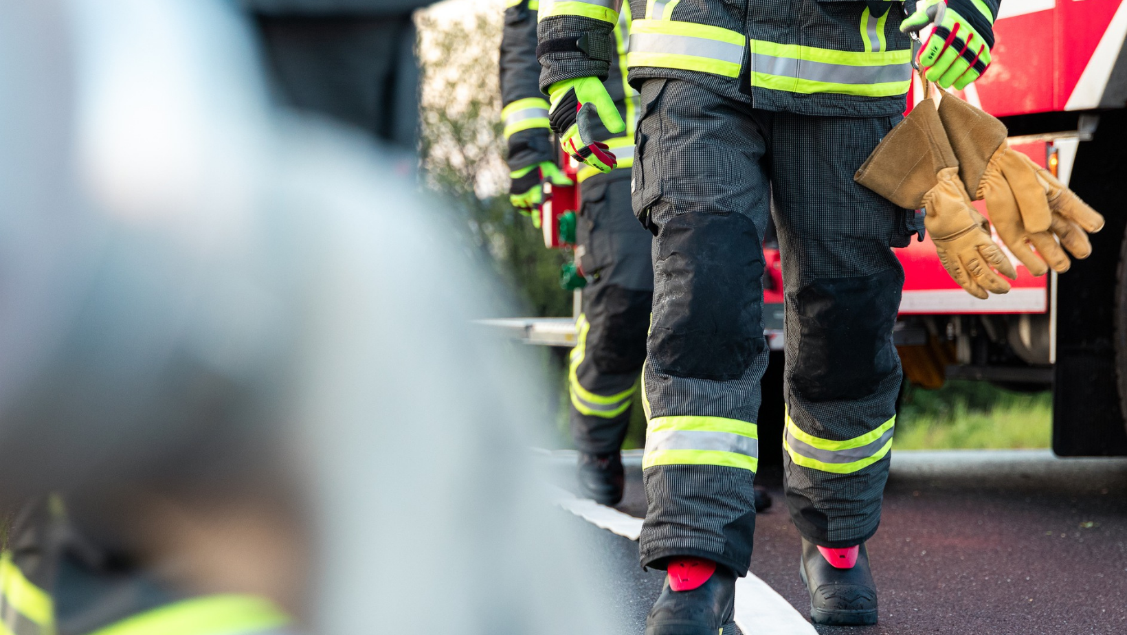 Palokuntalaiset kävelevät kohti kameraa sammutusasuissa. Kuvassa ei näy kasvoja.