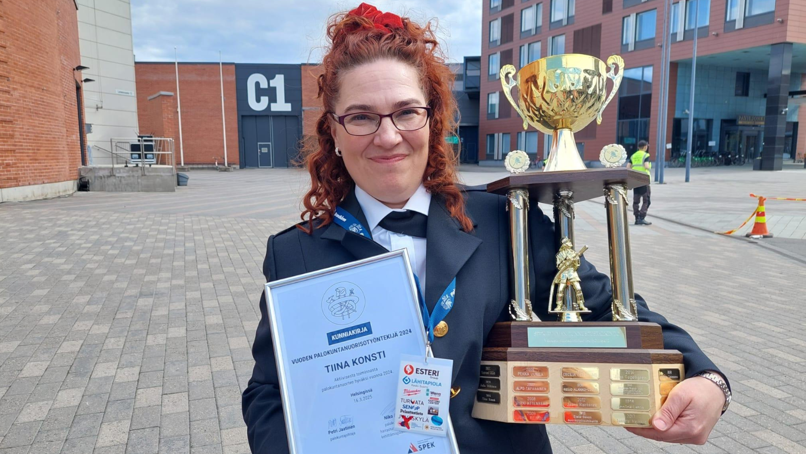 Vuoden palokuntanuorisotyöntekijä Tiina Konsti poseeraa palkinnon ja diplomin kanssa.