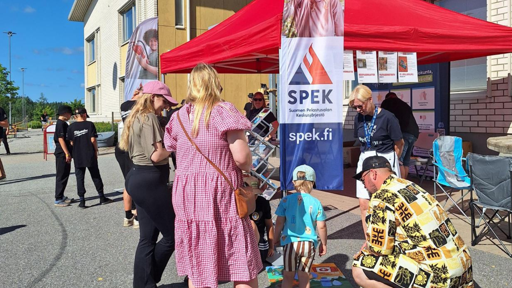 SPEKin teltta koulurakennuksen vieressä ja ihmisiä